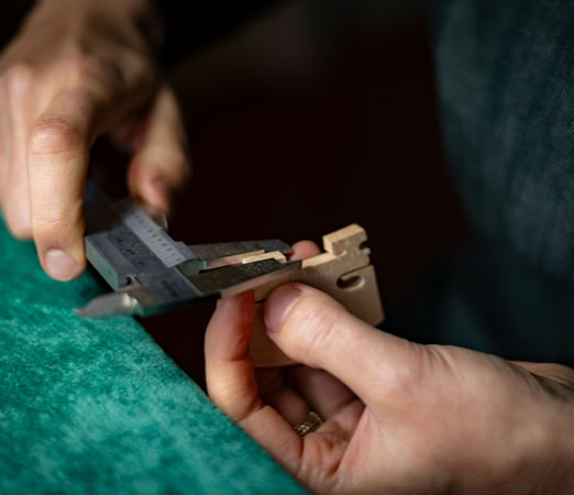 Das Bauteil einer Geige wird mit einem Me&szlig;schieber vermessen